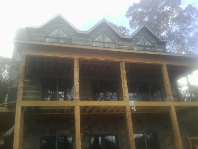Dormers and porch framing on a large log home under construction — Roof Coating work by our crew in Mc Alisterville