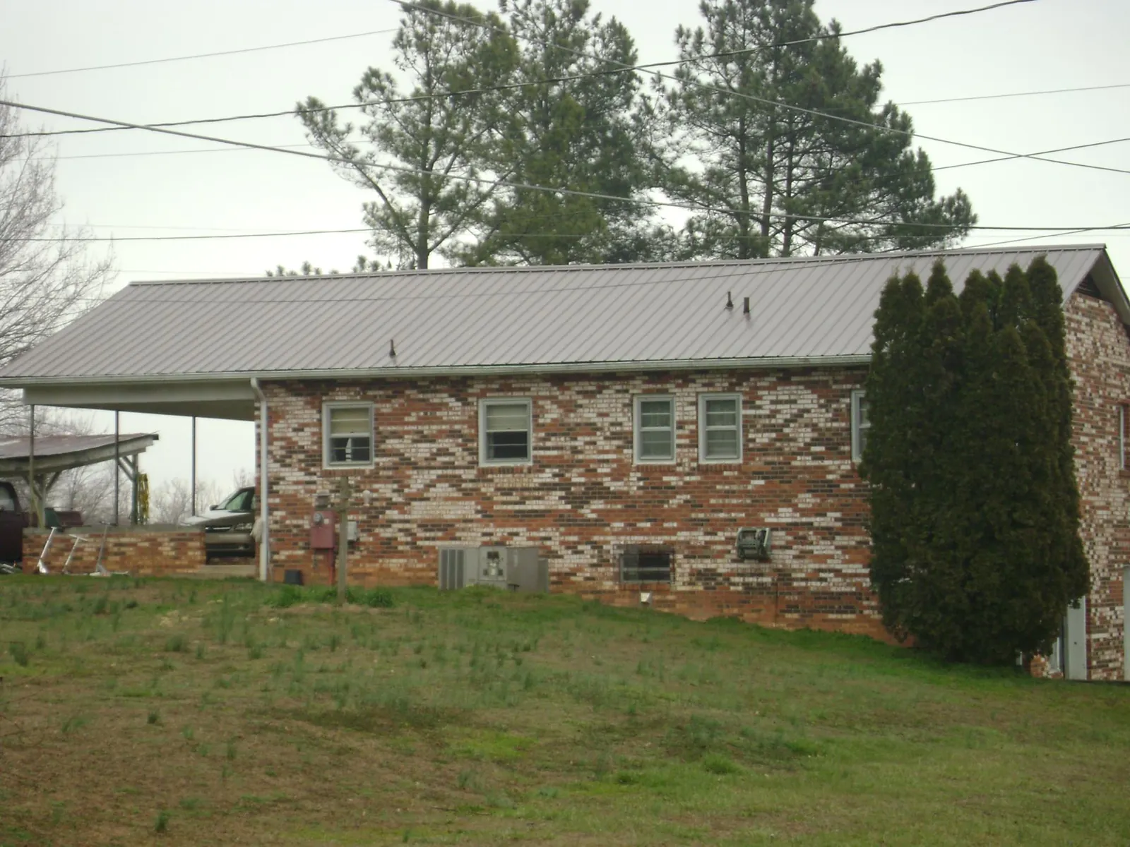 Gray metal roof on a brick split level home with a carport in Mc Alisterville
