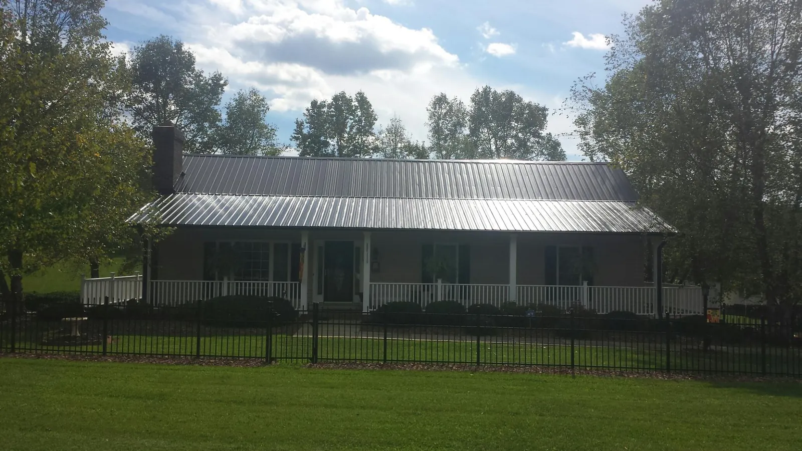 Gray metal roof on a brick ranch with a full width front porch — Gutter Guard Installation work by our crew in Mc Alisterville