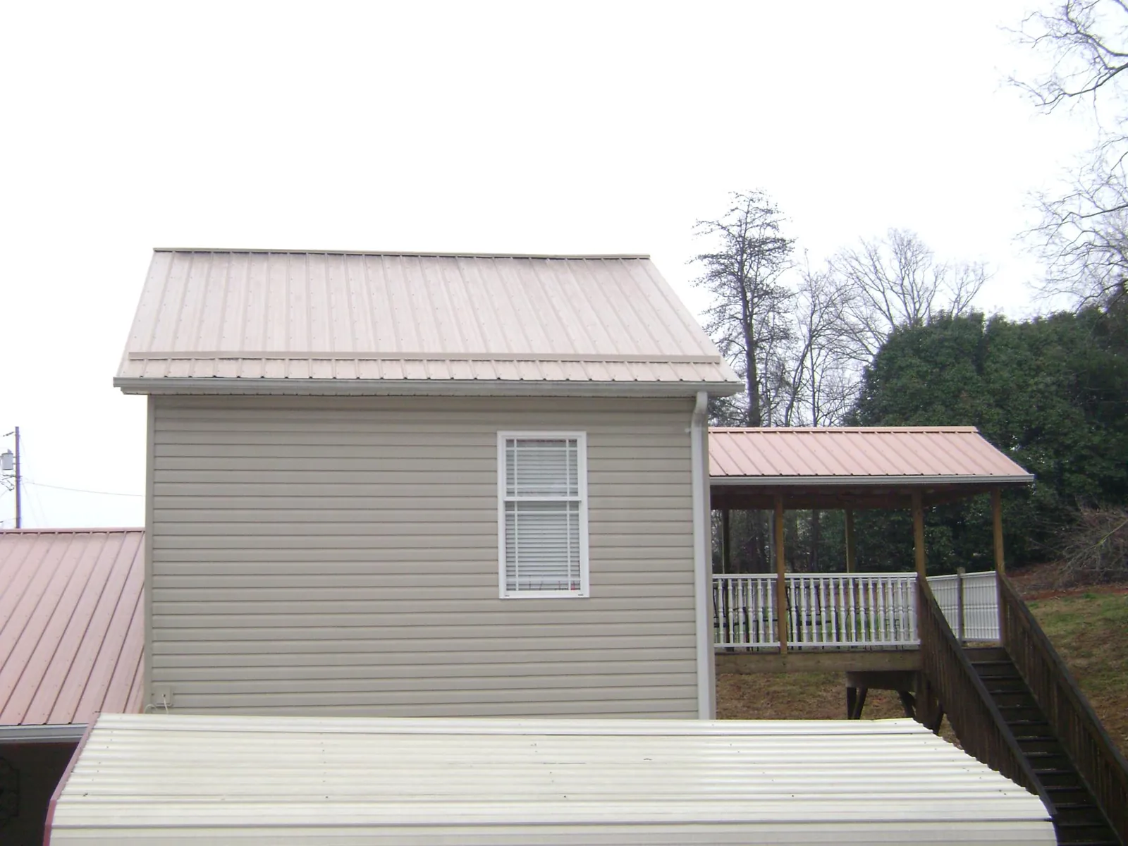 Tan metal roofs on a two story addition and attached porch, from a Roof Replacement job in Mc Alisterville