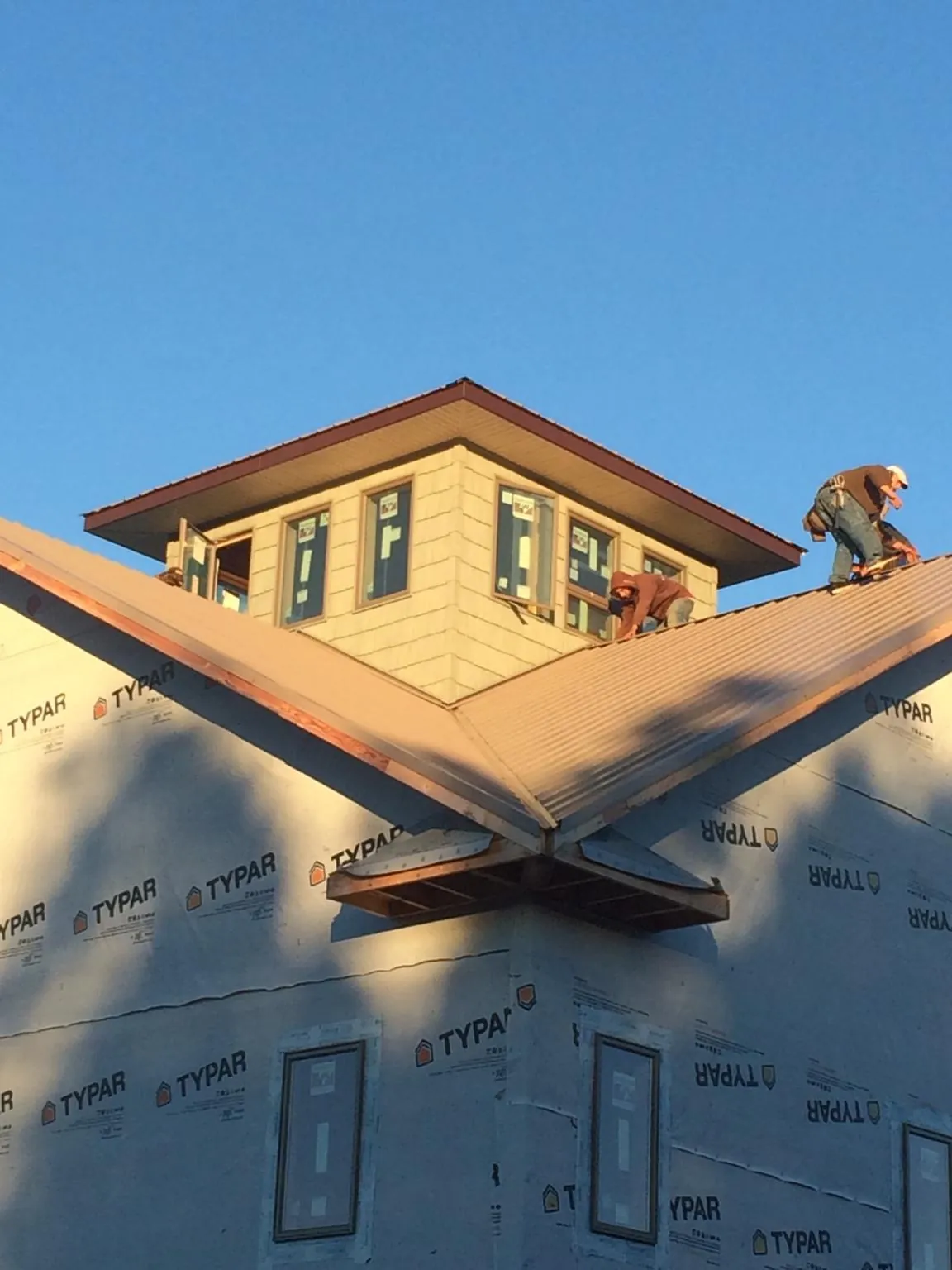 Roofers working around a rooftop cupola on a new metal roof at sunset — Roof Waterproofing in Mc Alisterville by Roofing Brothers